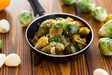 Brussel sprouts cooked with vegetables and spices, on a wooden table