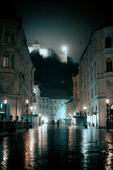 Ljubljana at night. Nighttime rain in Ljubljana, Slovenia, with castle on top. Two people with...