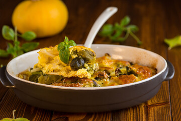 cauliflower and brussels sprouts casserole with cheese, in a ceramic dish on a wooden table