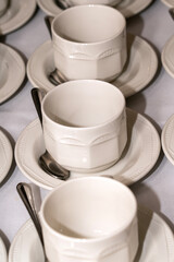 Empty white tableware crockery cups and saucers arranged on a table at a formal hospitality banqueting event or wedding, banquet stock photo image