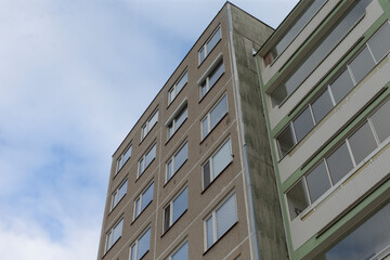 A contemporary residential building facade stands prominently against a dramatic, cloudy backdrop