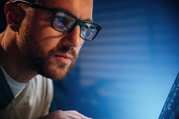 Focused on job. Male programmer is working indoors by a laptop