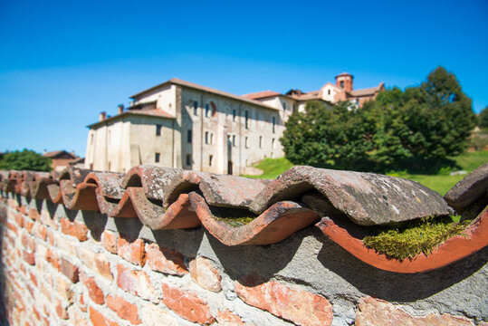 Close up of a brick wall with curvy tiles close to the famous abbey of Morimondo, Italy. Blue sky on the blurred background. Selective focus.