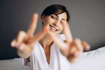 Young woman sitting in bed and smiling to camera
