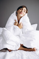 Woman in bed covered with white blanket