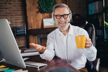 Photo of handsome mature mister talking call center drink tea dressed white shirt formalwear comfortable startup office loft room interior