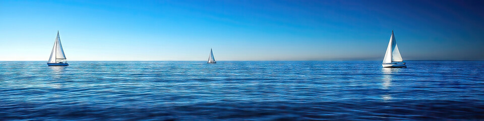 Obraz premium Seaside Serenity: A serene scene of a calm, blue ocean with white sails dotting the horizon.