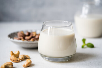 Dairy free cashew milk in a glass on concrete table, closeup view. Healthy alternative milk choice