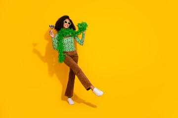 Charming young woman with curly hair in vibrant outfit posing joyfully against a bright yellow background.