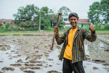 A proud farmer poses for a photo in a muddy rice field, showcasing his hard work