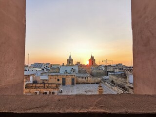 Fototapeta premium Sunrise over Valletta's rooftops, framing historic bell towers and casting a warm glow on the ancient Maltese architecture.