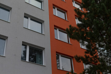 Obraz premium The building has a striking exterior with orange and grey walls, surrounded by lush trees