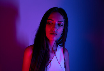 High Fashion model woman in colorful bright neon blue and purple lights posing in studio. Portrait of beautiful woman with trendy glowing make-up. Art design vivid style