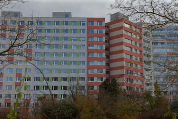 Colorful apartment buildings stand out in a bustling urban area, with picturesque trees in the...