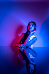 Naklejka premium High Fashion model woman in colorful bright neon blue and purple lights posing in studio. Portrait of beautiful woman with trendy glowing make-up. Art design vivid style