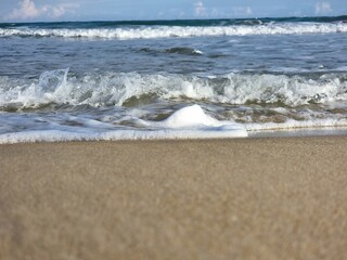 Sehr nahe Aufnahme von Wellen, die sanft auf den Strand rollen. Die Details des Wassers sind klar sichtbar, mit schäumenden Spitzen und der sanften Bewegung des Meeres.