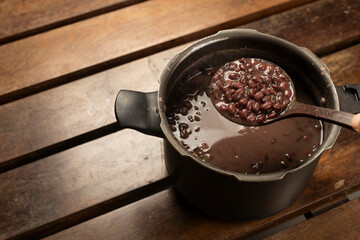Black Beans Cooked in the pressure cooker with a bean ladle on a wooden desk