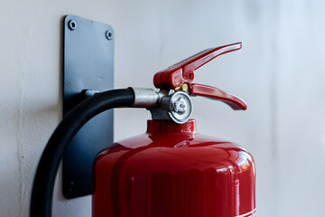 Fire alarm evacuation installation concept. A close-up image of a red fire extinguisher mounted on a wall, highlighting its nozzle and hose, symbolizing safety and fire prevention.