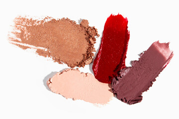 Eyeshadow, lipstick, lip gloss, scattered makeup particles, and foundation smears in a cosmetic texture.