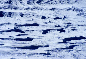 Artistic image that portrays snow photographed against the sun that creates strong contrast effects with underexposed blue tones