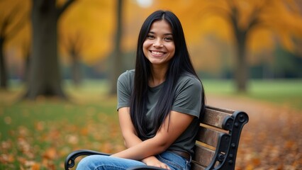 Native American woman with long black hair smiling seated on park bench among colorful autumn foliage