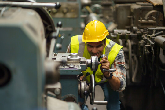industrial Engineer indian man control lathe machine in industry manufacturing large factory . asian india labor worker male in hard hat and goggles working metal work in workplace . banner copy space