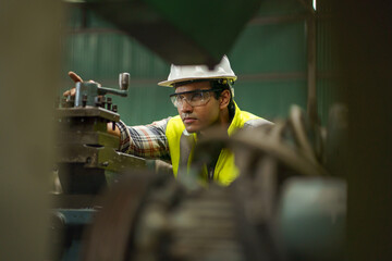 industrial Engineer indian man control lathe machine in industry manufacturing large factory . asian india labor worker male in hard hat and goggles working metal work in workplace . banner copy space