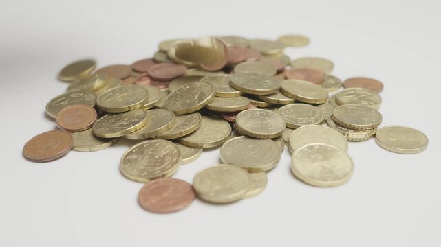 A collection of various euro coins scattered across a white surface, symbolizing finance, currency, and wealth. The image represents monetary value and European economic concepts.