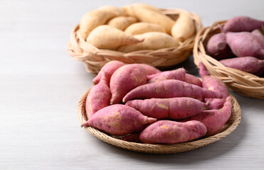 Organic raw sweet potatoes from local farmer market in basket on white table