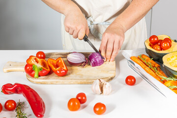 Cooking soup from pumpkin, pepper, tomato, onion, garlic using a knife and cutting board