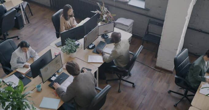 Top view of busy office room with employees diverse team working at desks using computers. Modern workplace and successful enterprise concept.