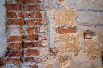 stara ściana z cegły częściowo pokryta tynkiem z malowidłem © siwyk