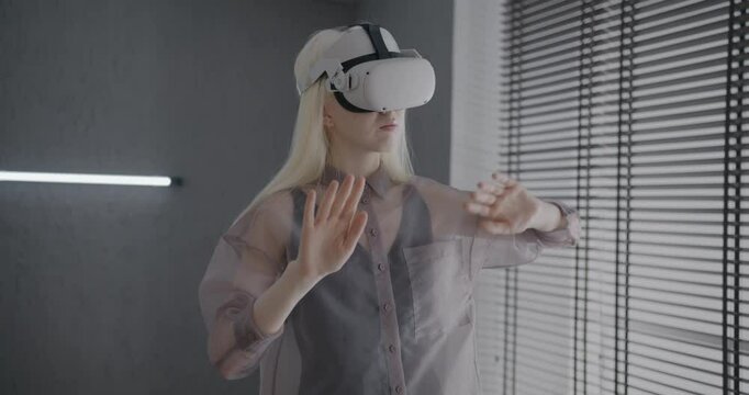 Slow motion of albino lady wearing virtual reality glasses gesturing standing in apartment enjoying gaming device and new experience. Modern technology and people concept.