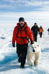 A man is walking with a polar bear on a leash. The bear is white and he is young. The man is wearing a red jacket and a black backpack. The scene is set in a snowy environment, with the man