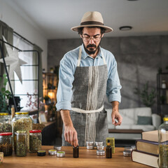 Adult young man in apron hold dropper and bottle in workshop