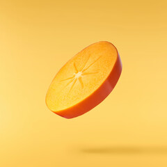 Fresh ripe Persimone fruit falling in the air isolated on yellow background, food levitation or zero gravity conception