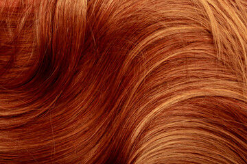 Naklejka premium Red hair close-up as a background. Women's long orange hair. Beautifully styled wavy shiny curls. Hair coloring bright shades. Hairdressing procedures, extension.
