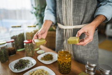 close up of man herbalist in apron hold organic soap in workshop
