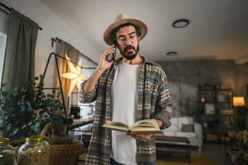 adult man herbalist read a book about herbs and talk on mobile phone