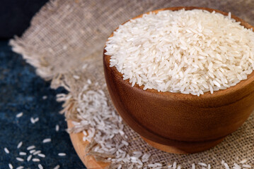 White rice in wooden bowl on dark background.