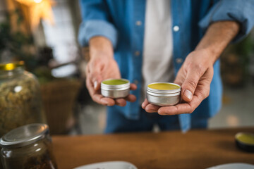 close up of man hands hold organic natural salve in workshop