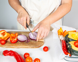 Cooking soup from pumpkin, pepper, tomato, onion, garlic using a knife and cutting board