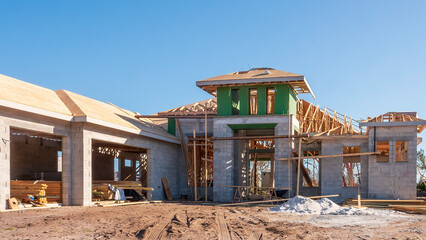 Street view of upscale single-family house under construction, with stacks of lumber in garages...