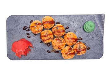 Sushi rolls baked on a black slate plate stand out against a white background.