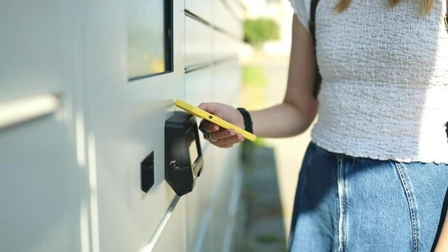 Woman using automated self service post terminal machine or locker to deposit the parcel for storage. High quality photo