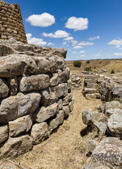 Majestic ruins of nuraghe Piscu in sardinia, italy, stand tall against a vibrant blue sky,...