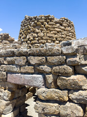 Majestic ruins of nuraghe Piscu in sardinia, italy, stand tall against a vibrant blue sky, showcasing ancient megalithic architecture