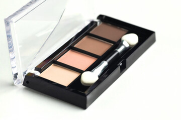 A palette of beige, brown warm eyeshadow with an applicator on a white background