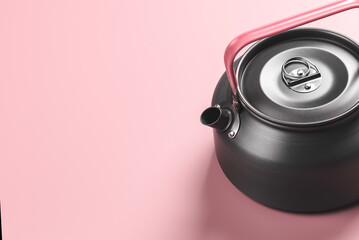 Tin kettle on pink background.