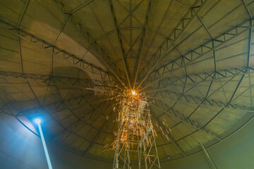 Male worker metal cutting spark on tank roof steel plate with flash of cutting light close up wear protective gloves